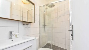 A modern bathroom with a glass-enclosed shower, a white sink, and a toilet.