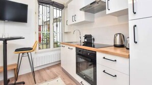 A compact kitchen with white cabinets, a black stove, and a wooden countertop.