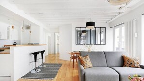 A modern living room with a grey sofa, a coffee table, and a dining area with a small table and chairs.