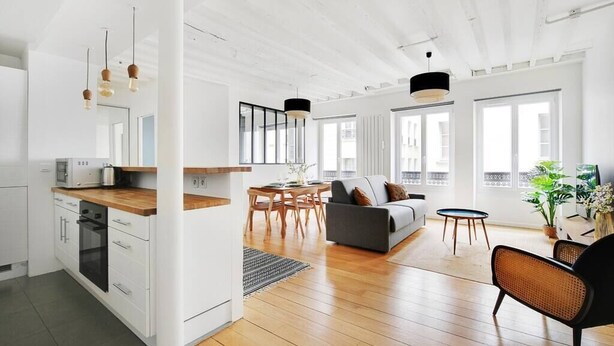 A modern kitchen with white cabinets, a wooden countertop, and a dining area with a table and chairs.