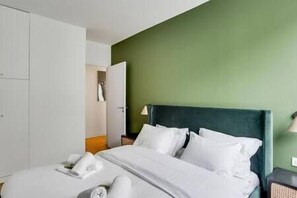 A hotel room with a bed, pillows, and a nightstand.