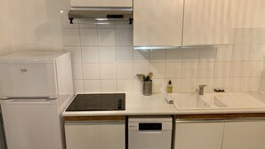 Uma cozinha equipada com geladeira, lava-louças, micro-ondas e pia com torneira.