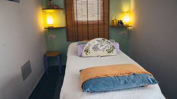 Cozy bedroom with a single bed, stool, and wall-mounted lamps.