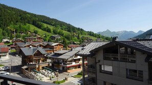 A mountain village with traditional wooden houses, a café, and a view of the surrounding hills.