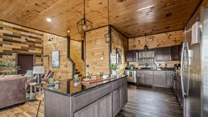 A modern kitchen with wooden walls, a central island, and stainless steel appliances.