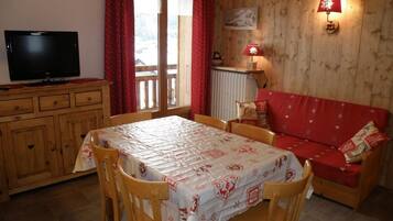 Une pièce confortable avec une table à manger, des chaises, un canapé, un téléviseur et une lampe.