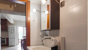 Ein modernes Badezimmer mit Toilette, Waschbecken mit Spiegel darüber und einer Kaffeemaschine auf der Ablagefläche.
