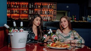 Dos personas sentadas en un bar con un cubo de bebidas y botellas de Stella Artois.