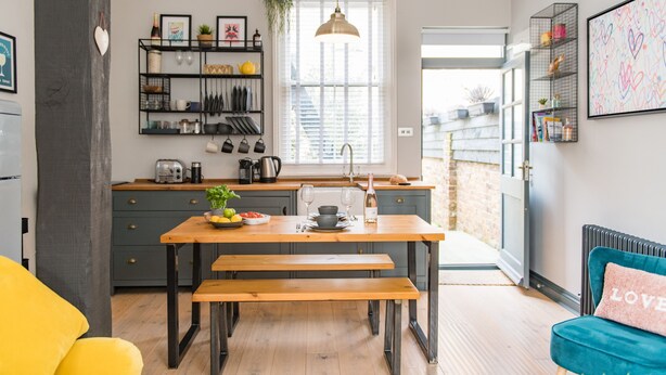 A modern kitchen with a wooden table and bench, a hanging pendant light, and a view to the outside. - The Little Cottage, Whitstable (Whitstable)