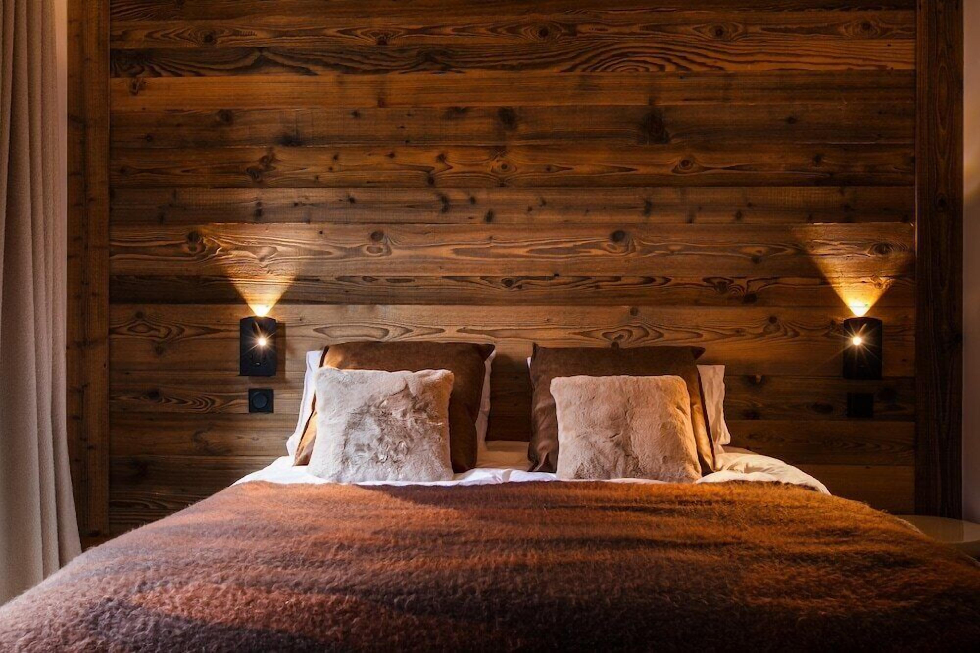 A cozy room with a wooden headboard, two wall-mounted lights, and a fluffy bedspread.