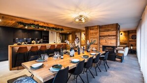 A modern dining area with a wooden table set for a meal, surrounded by black chairs. - PEARL 201 | LES GETS | 14 pers.  | Central (Les Gets)