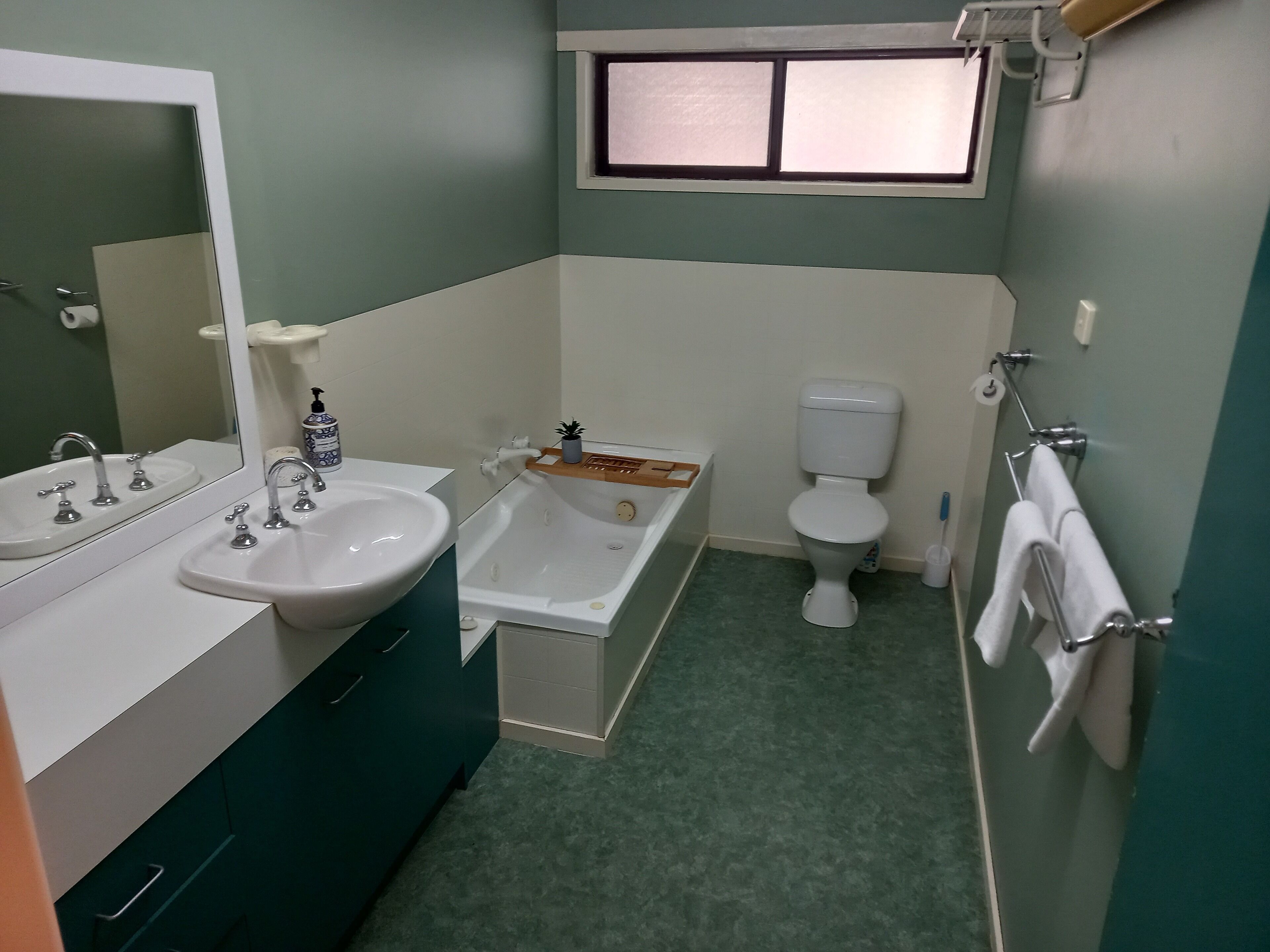 A bathroom with a sink, mirror, bathtub, toilet, and a window.