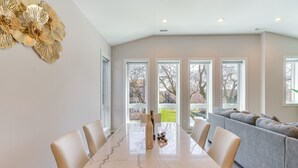 A dining area with a marble table, white chairs, and a grey sofa. - 7 Mi to Downtown: Luxe Chicago Condo (Chicago)