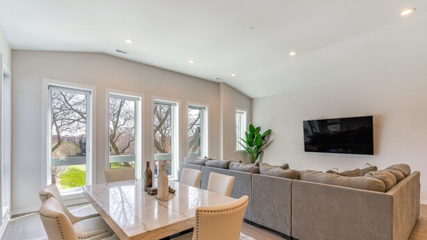 A modern living room with a grey sofa, a dining table with chairs, and a flat-screen TV mounted on the wall. - 7 Mi to Downtown: Luxe Chicago Condo (Chicago)