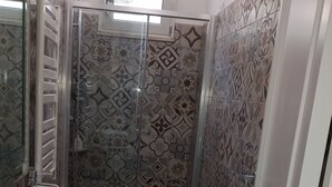 A bathroom with a white sink, a glass-enclosed shower, and patterned tiles. - Our le Spiagge beachfront property boasts a terrace overlooking the sea. (Letojanni)