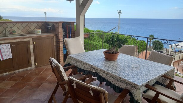 A patio with a table, chairs, and a potted plant. - Our le Spiagge beachfront property boasts a terrace overlooking the sea. (Letojanni)