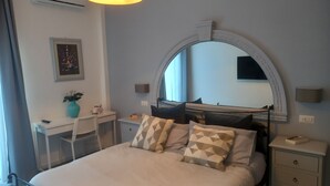 A hotel room with a bed, a desk, a chair, a mirror, and a window. - Our le Spiagge beachfront property boasts a terrace overlooking the sea. (Letojanni)