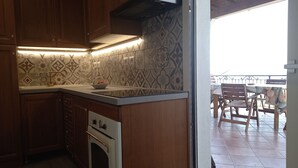 A kitchen with patterned tiles, wooden cabinets, and a view of an outdoor patio with a table and chairs. - Our le Spiagge beachfront property boasts a terrace overlooking the sea. (Letojanni)