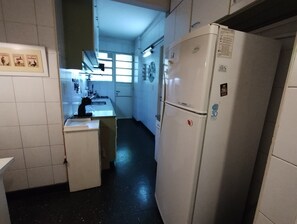 A compact kitchen with white cabinets, a sink, and a refrigerator.