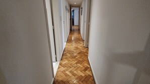 A hallway with a wooden herringbone floor and white walls. - Recoleta tres dormitorios (Buenos Aires)
