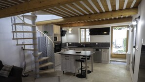 A modern kitchen with a central island, a spiral staircase, and a dining area with a wooden table. - AU Coeur DU Luberon Idealement Situe Pour Visiter LE Region (Gargas)