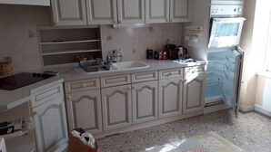 Een keuken met witte kasten, een inbouwoven en een spoelbak.