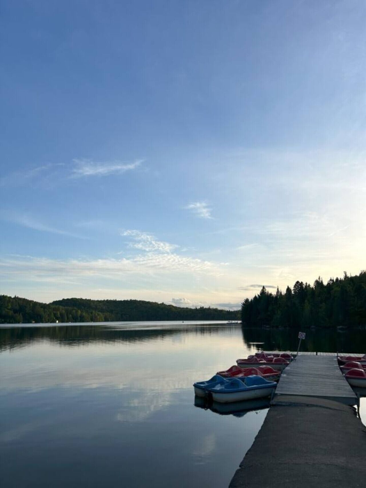 Tyyni järvi, jossa on laituri ja useita pieniä veneitä.