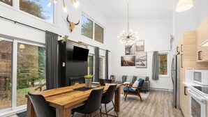 Un interior moderno con comedor, chimenea, televisor y cocina.