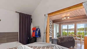 Een slaapkamer met een groot bed, een badkamer, een zithoek met uitzicht en een houten plafond.