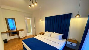 A bedroom with a large bed, bedside tables, a mirror, and a hanging light fixture. - City Heart Luxury Apartment  (Kutaisi)