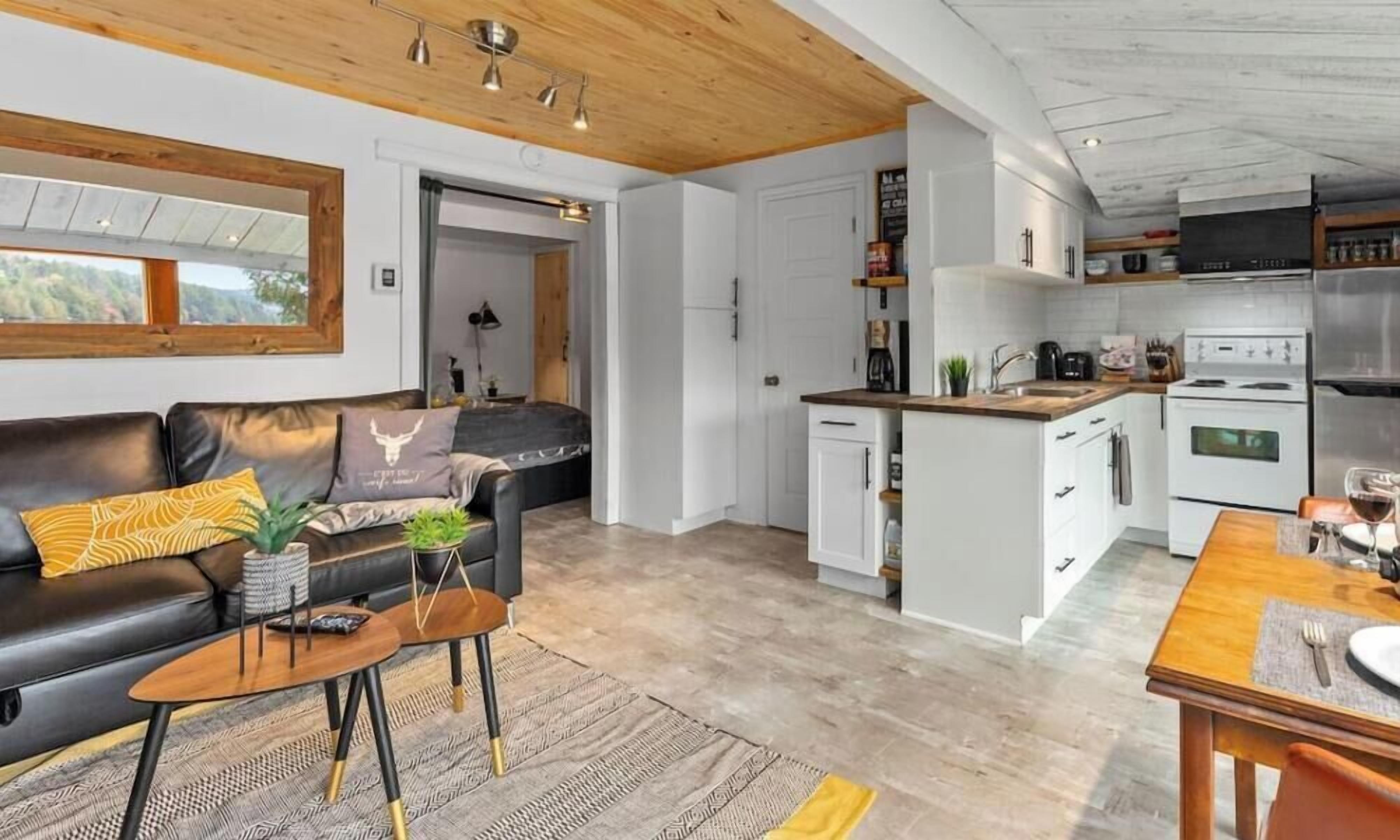 Une cuisine moderne avec des meubles blancs, une table à manger en bois et un four encastré.