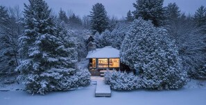 Une cabane entourée d’arbres couverts de neige.