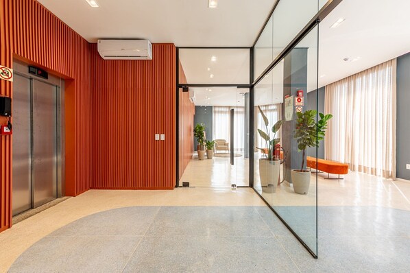 Un hall d’hôtel moderne doté d’un sol incurvé, d’un comptoir d’accueil, d’un espace salon et d’une cloison en verre.