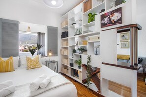 Ein Hotelzimmer mit Bett, großem Fenster, Bücherregal und Blick auf die Stadt.