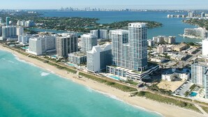Een kuststadsgezicht met hoge hotels, een strand en een jachthaven.