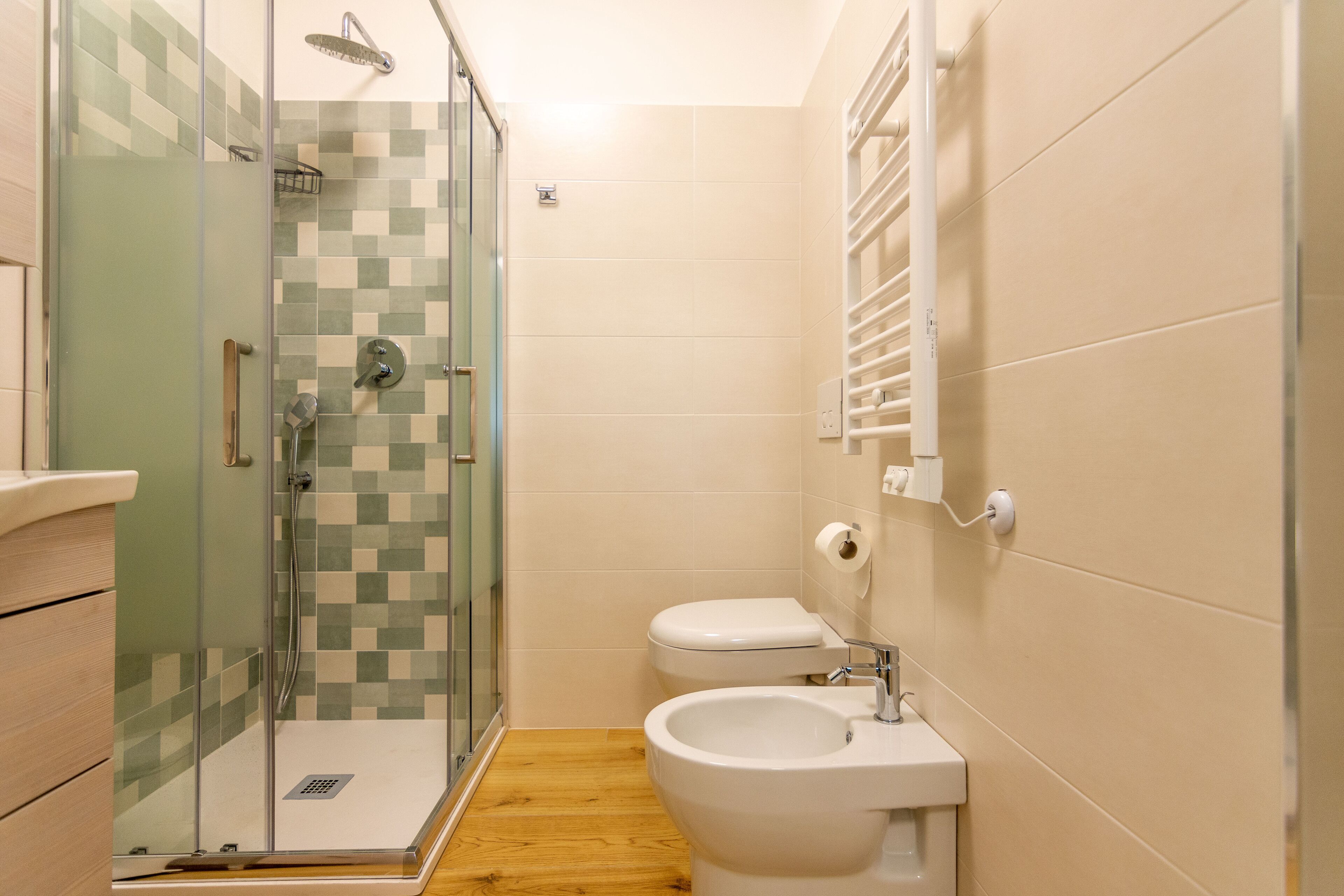 Un bany amb dutxa d'envidriament, un vàter i un bidet.