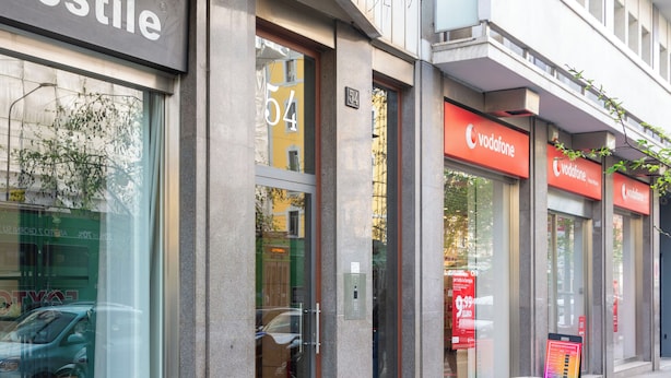 A storefront with a glass door, a number '54' above it, and a Vodafone sign. - Italianflat - Vittoria Suite (Milan)