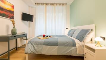 Une chambre à coucher avec un lit, un bureau, une télévision et une table de chevet.