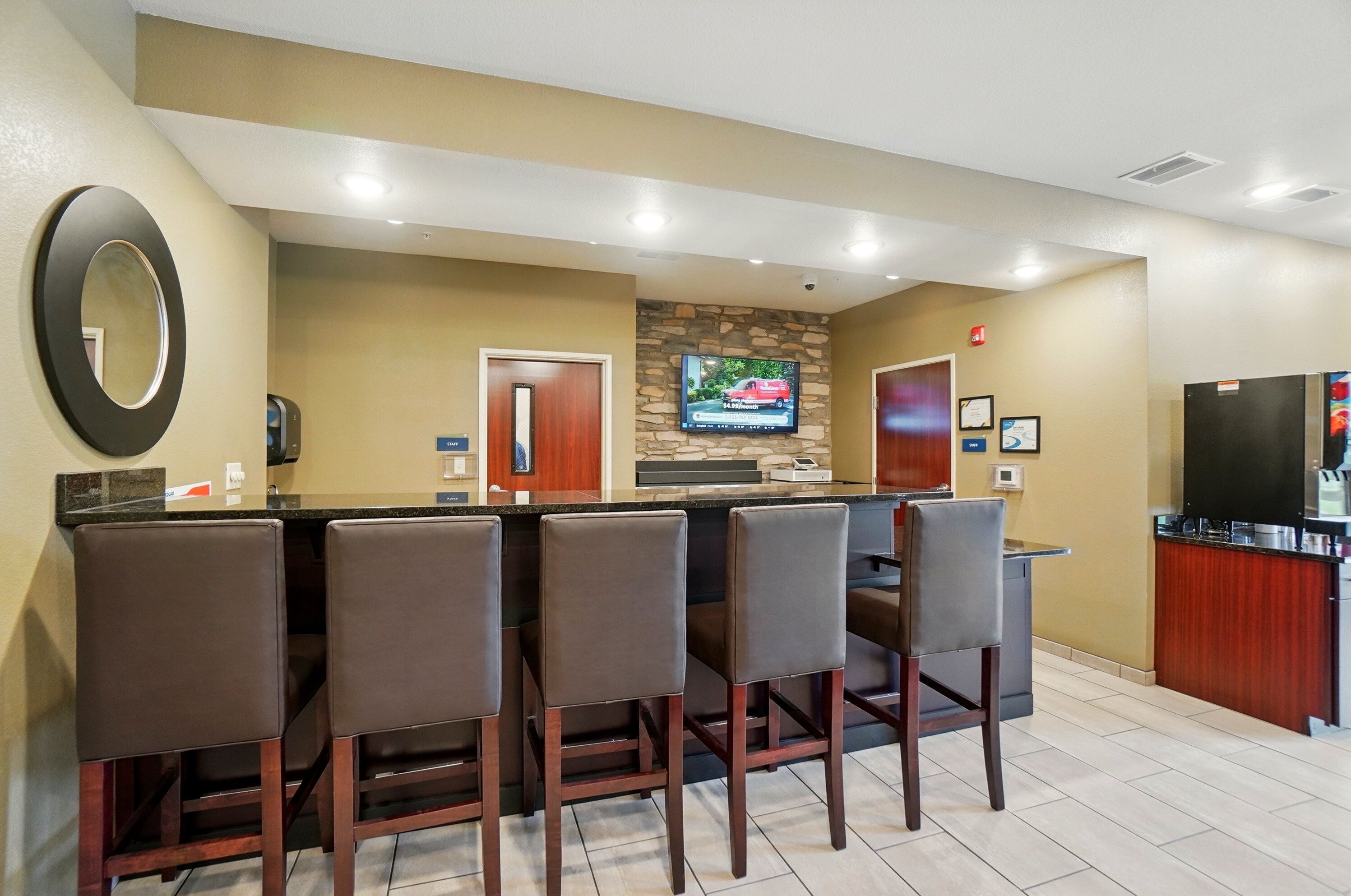 A bar area with a stone accent wall, a flat-screen TV, and a refrigerator.