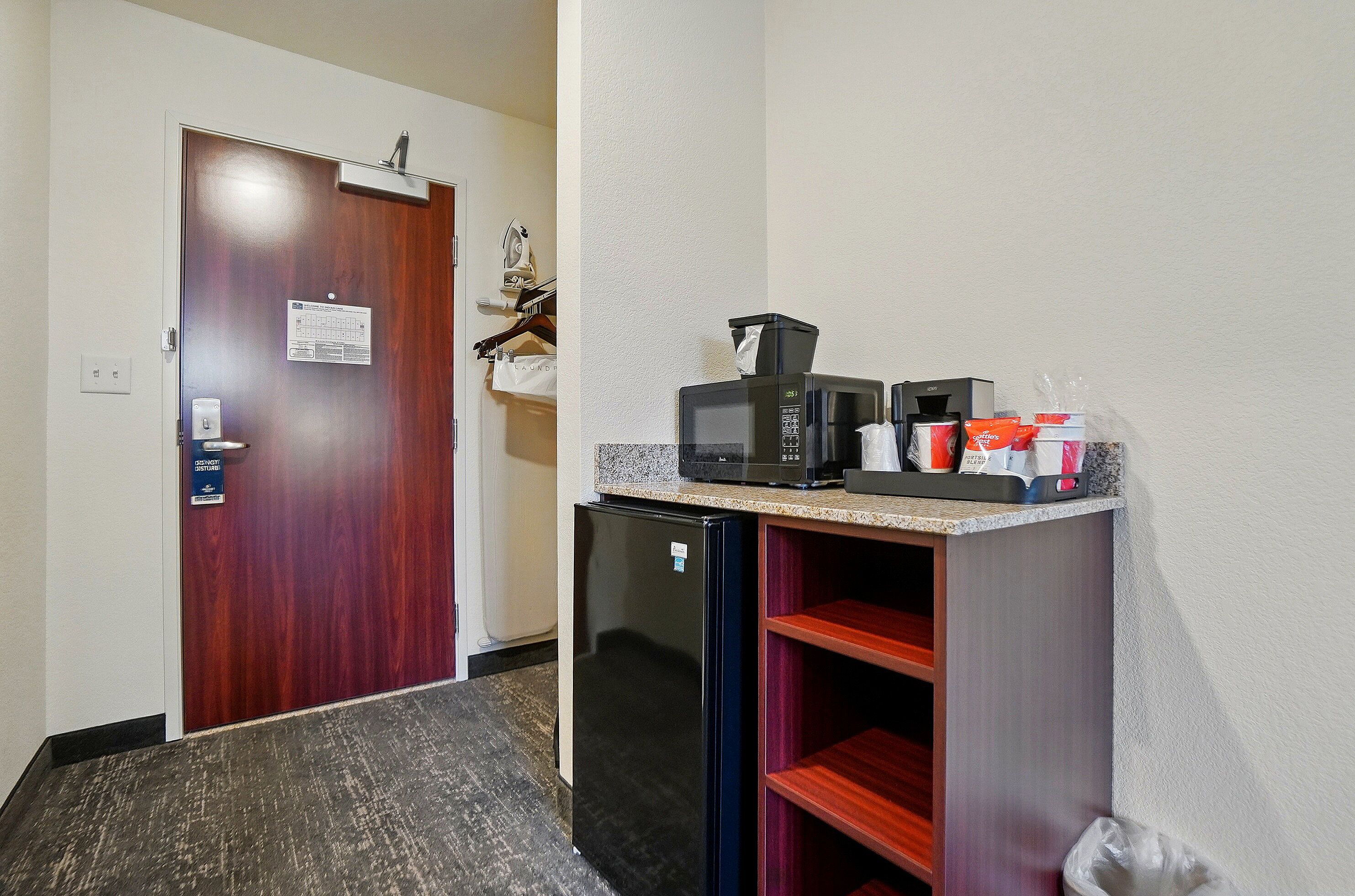 A compact kitchenette with a refrigerator, microwave, and coffee maker.