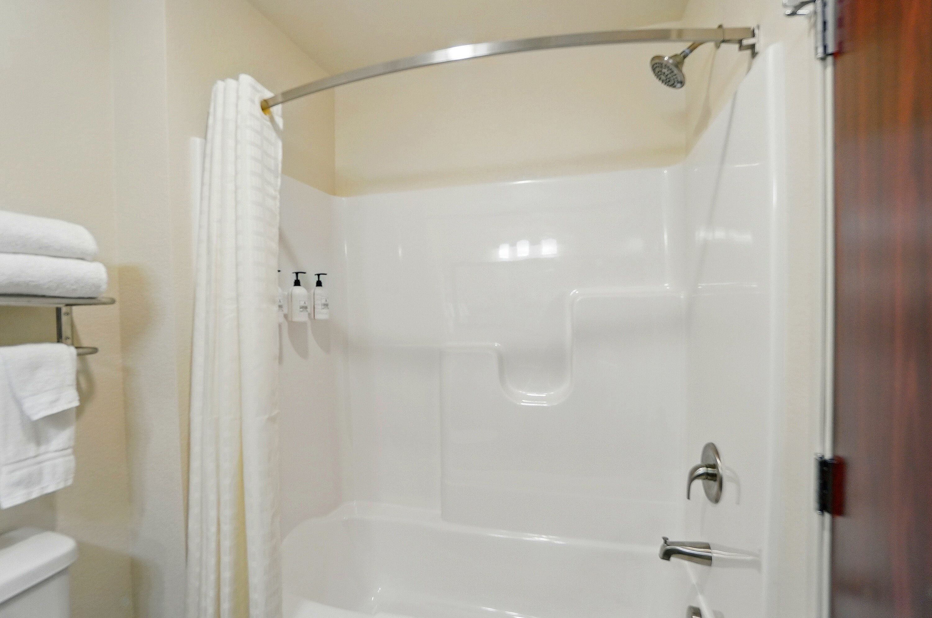 A shower area with a glass door, a towel rack with towels, and a showerhead.