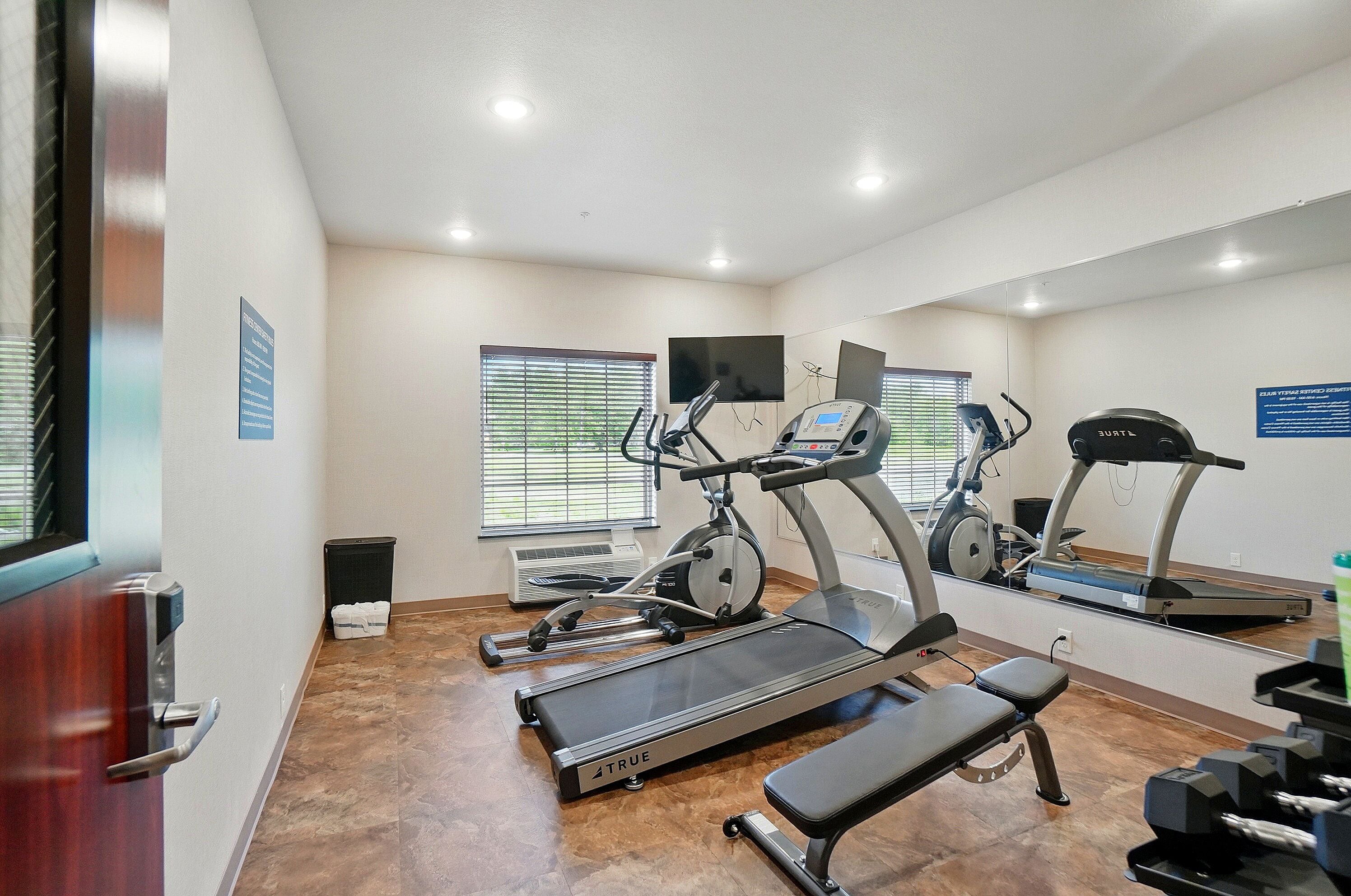 A gym with treadmills, a stationary bike, and a bench.