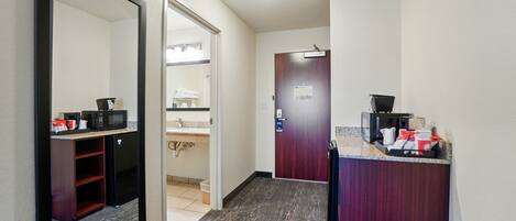 A hotel corridor with a microwave, coffee machine, and a trash bin.