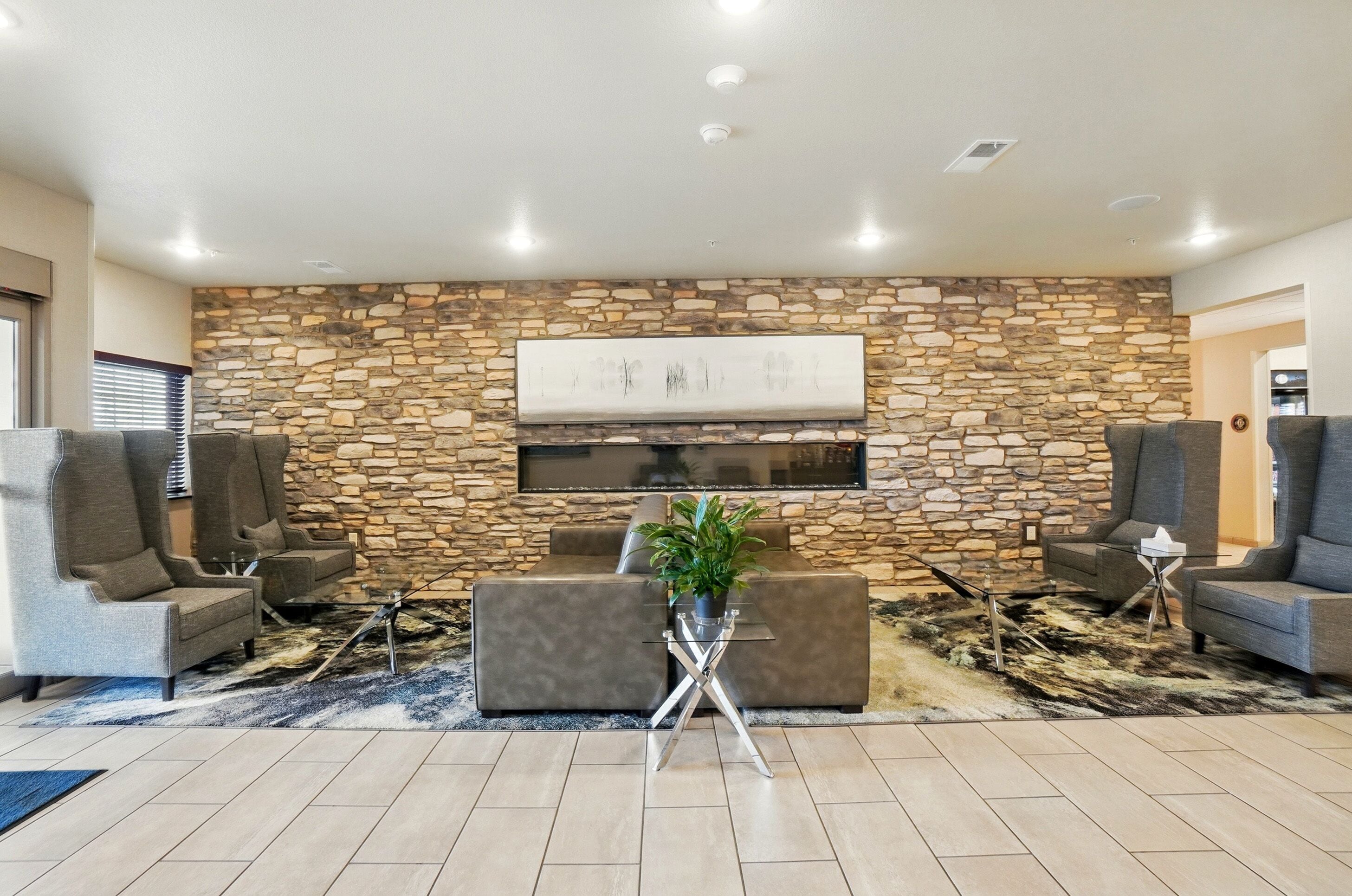 A modern lobby with a stone wall, comfortable seating, a flat-screen TV, and a potted plant.
