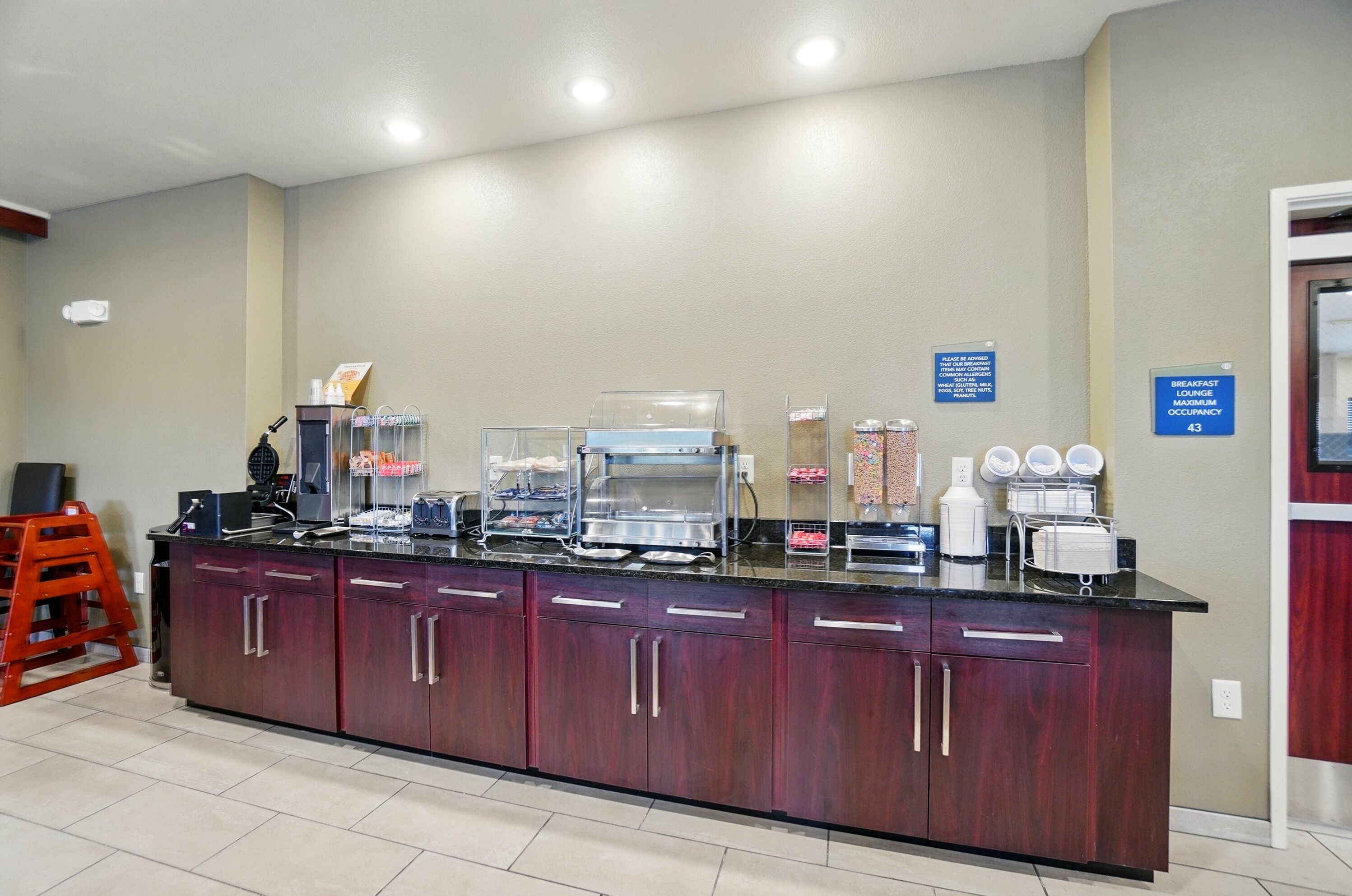 A breakfast bar with a coffee machine, a juice dispenser, and a sign indicating maximum occupancy.