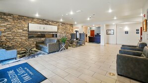 A spacious lobby with a stone wall, comfortable seating, a reception desk, and a large window. - Cobblestone Hotel & Suites-RussellsPoint (Russells Point)