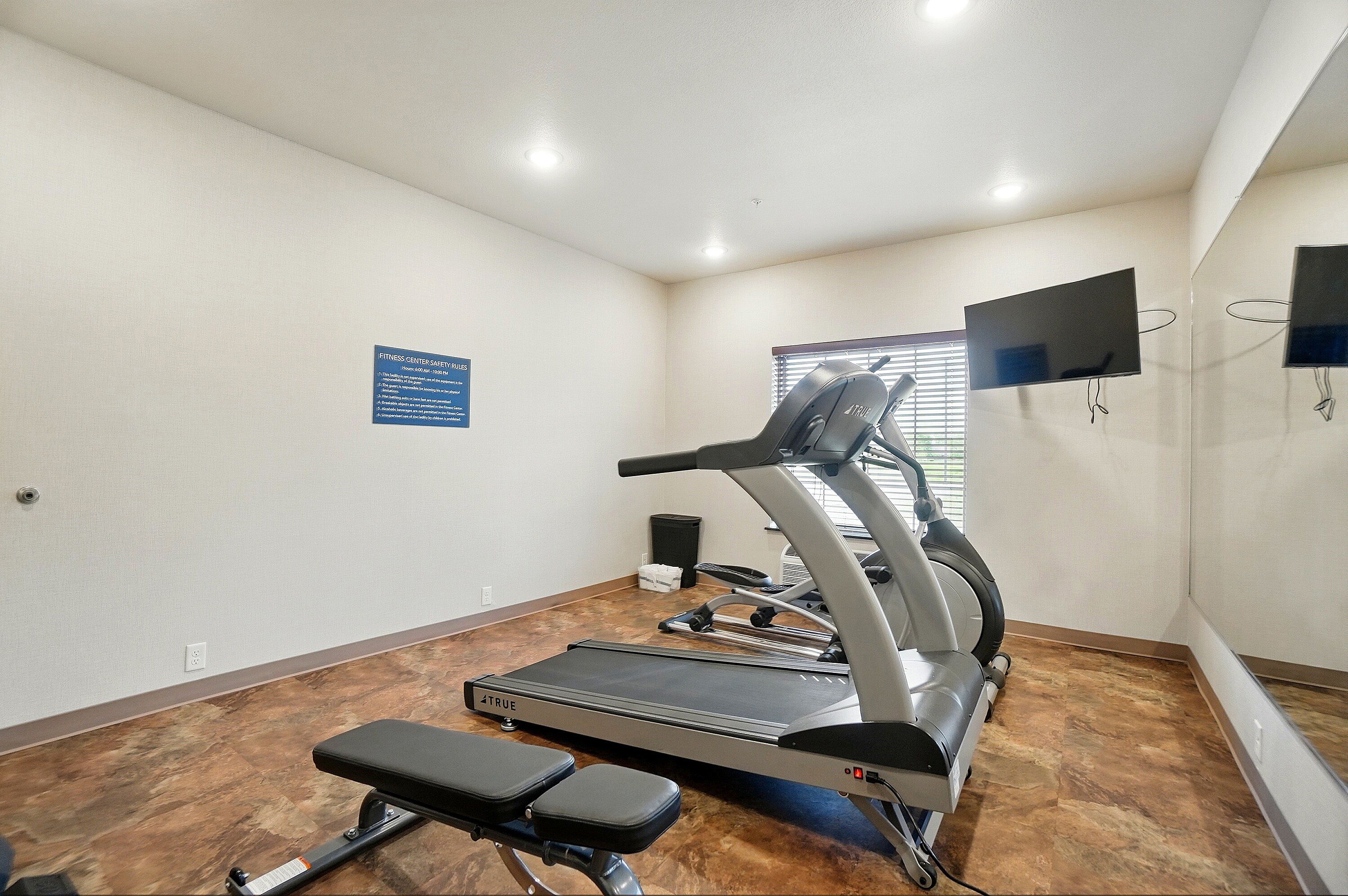 A fitness center with a treadmill, bench, and a sign on the wall.
