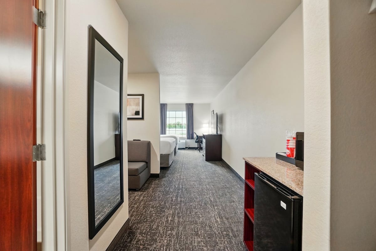 A hotel room with a bed, a desk, a chair, and a window with curtains.