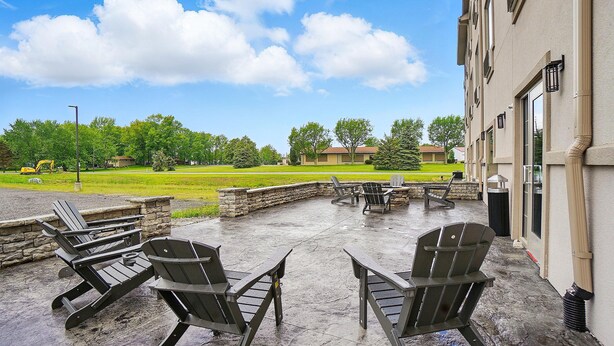 An outdoor patio with Adirondack chairs, a fire pit, and a stone wall. - Cobblestone Hotel & Suites-RussellsPoint (Russells Point)