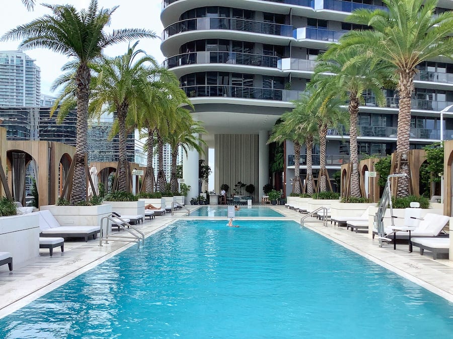 Una piscina al aire libre, sombrillas, sillones reclinables de piscina